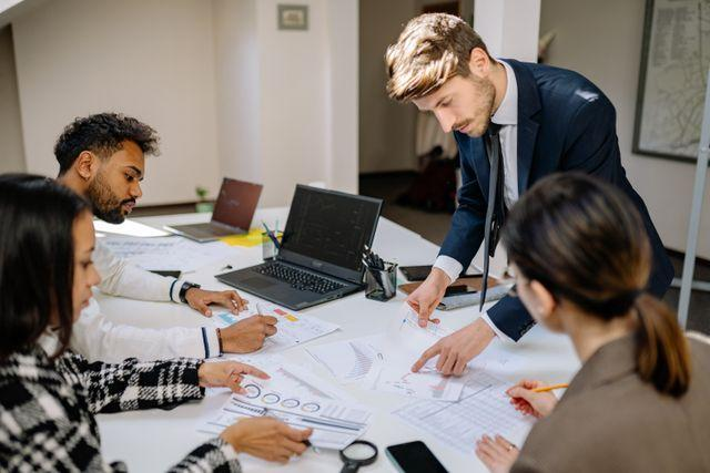 Four people consulting charts at a desk